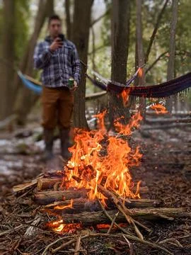A roaring fire in a forest with a man taking a picture in the background Stock Photos