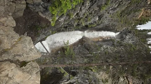 Roaring tall white waterfall between gray rocks and trees  Stock Footage 152482929