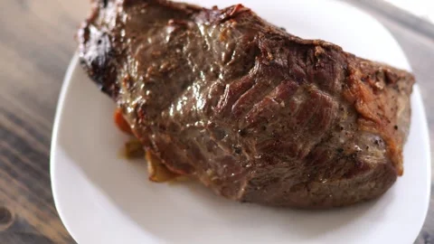 Roast beef with brown crust with vegetables steaming on a plate Stock Footage 279223164