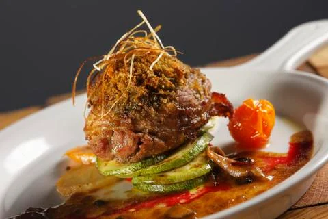 Roast beef wrapped with bacon in a cherry tomato and pumpkin sauce. Stock Photos