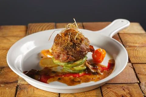 Roast beef wrapped with bacon in a cherry tomato and pumpkin sauce. Stock-Fotos