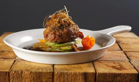 Roast beef wrapped with bacon in a cherry tomato and pumpkin sauce. Stock Photos