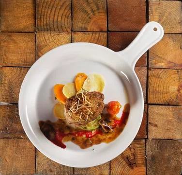 Roast beef wrapped with bacon in a cherry tomato and pumpkin sauce. Stock Photos