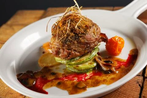 Roast beef wrapped with bacon in a cherry tomato and pumpkin sauce. Stock Photos