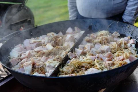 Roast cabbage and fish is cooked in a huge cauldron in nature Stock Photos
