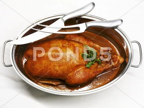 Roast goose in roasting dish, carving knife and fork Stock Photos