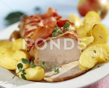 Roast loin of pork with apple wedges and bacon Stock Photos