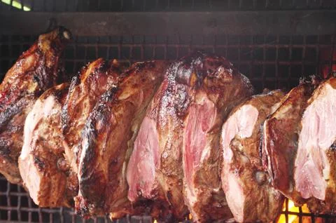 Roast meat by fire with flames, traditionally eaten at different family feast Stock Photos