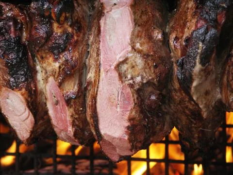 Roast meat by fire with flames, traditionally eaten at different family feast Stock Photos