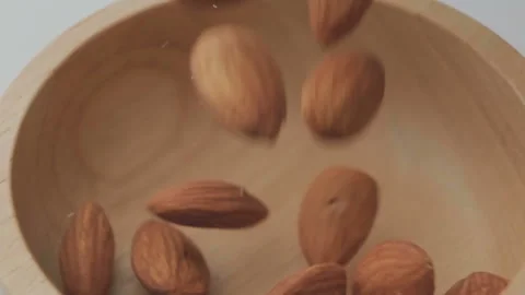 Roasted almond seeds falling down into wooden bowl Stock Footage 142676856