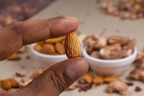 Roasted almonds nuts in hand on light background isolation. Stock Photos