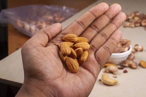 Roasted almonds nuts in hand on light background isolation. 스톡 사진
