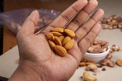 Roasted almonds nuts in hand on light background isolation. Stock-Fotos