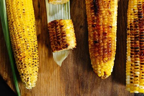 Roasted barbecue corn. Grilled corn on a dark wooden background. Slices of Stock Photos
