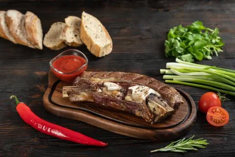 Roasted beef on the bone on a board for serving. Stock Photos