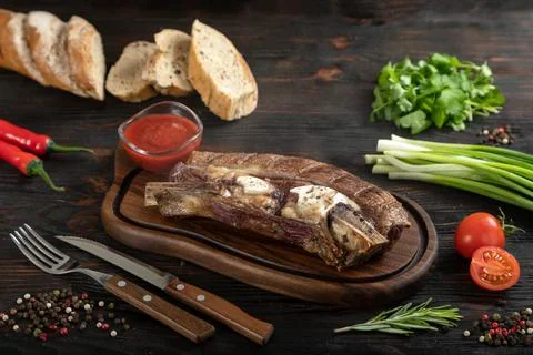 Roasted beef on the bone on a board for serving. Stock Photos