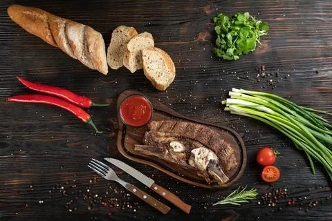 Roasted beef on the bone on a board for serving. Stock Photos