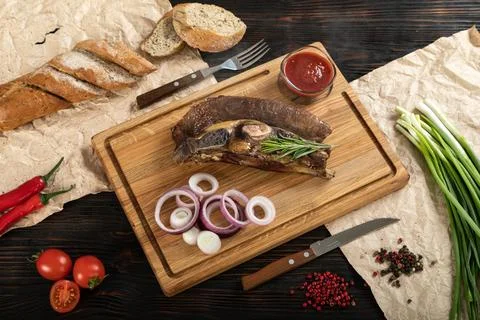 Roasted beef on the bone on a board for serving. Stock Photos