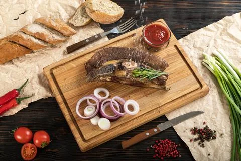 Roasted beef on the bone on a board for serving. Stock Photos