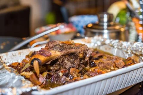 Roasted beef rib steak with bone in roasting tray on busy kitchen table Stock-Fotos