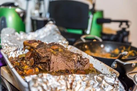 Roasted beef rib steak with bone in roasting tray on busy kitchen table Foto stock