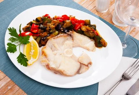 Roasted blue shark steak with vegetable saute, lemon and greens Stock Photos