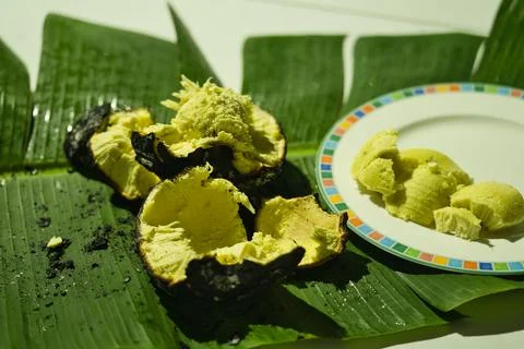 Roasted Bread fruit  under, break open on banana leaves, and in serving pla Stock Photos