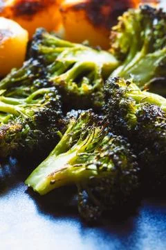 Roasted broccoli served on a plate with some roasted potatoes Stock Photos