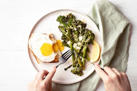 Roasted broccolini with fried egg on the plate. Stock Photos