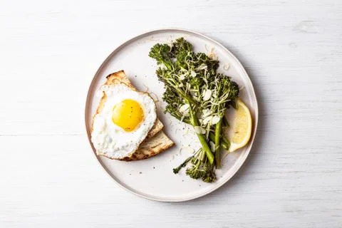 Roasted broccolini with fried egg on the plate. Stock Photos