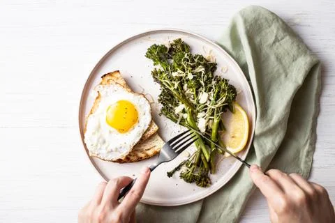 Roasted broccolini with fried egg on the plate. Stock Photos