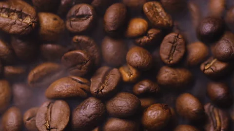 Roasted brown and black coffee grains during the roasting process. Stockbeeldmateriaal 101549550