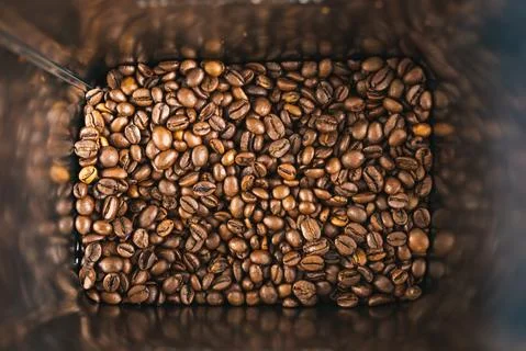 Roasted brown coffee beans inside square tin can as a background. Stock Photos
