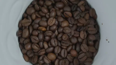 Roasted brown coffee beans rotate into white ceramic coffee machine part Stock Footage 167839084