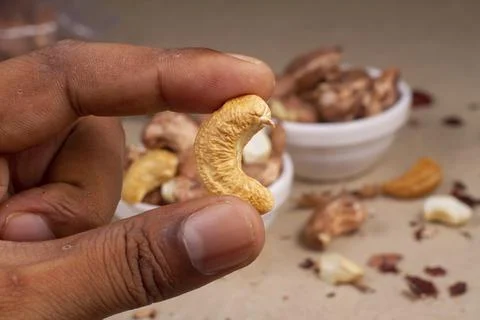 Roasted cashew nuts in hand on light background isolation. Stock Photos