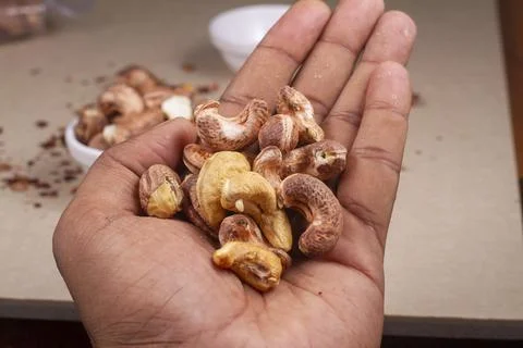 Roasted cashew nuts in hand on light background isolation. Stock Photos