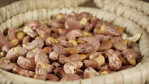 Roasted Cashews Fall from Above on a Rotating Pile on a Wicker Plate. Crunc.. Stock Footage 319027072