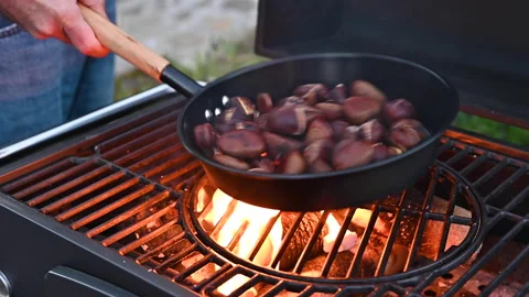 Roasted chestnuts and maroni over the fire in a special steel pan. Traditional Stock Footage 166176755