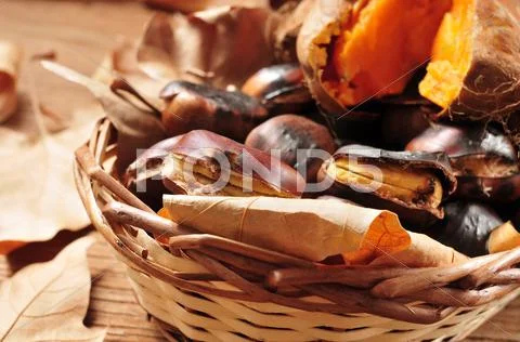Roasted chestnuts and roasted sweet potatoes in a basket Stock Photos