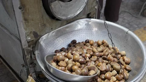 Roasted chestnuts arranged inside a metal bowl placed on a selling surface at a 스톡 동영상 334661177