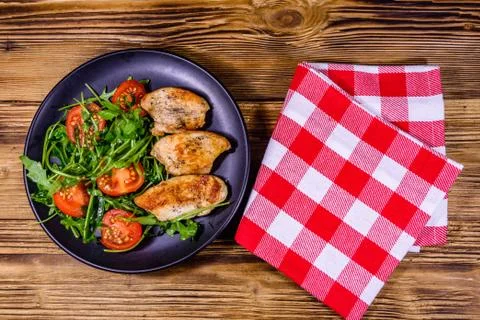 Roasted chicken breasts and salad with arugula and cherry tomatoes in a black Stock Photos