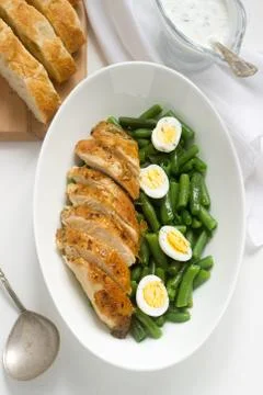 Roasted chicken breasts served with fried egg and boiled green beans. Stock Photos