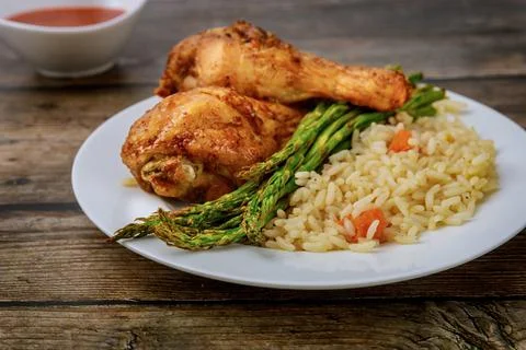 Roasted chicken drumsticks with rice on rustic wooden background, Stock Photos