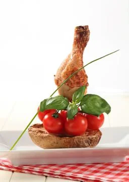 Roasted chicken leg with cherry tomatoes and basil Stock Photos