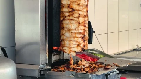 Roasted chicken meat from a rotating spit and prepares traditional street food 스톡 동영상 332762371