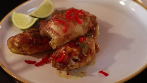 Roasted chicken thigh dish being garnished with chili and peanuts Stock Footage 274075710