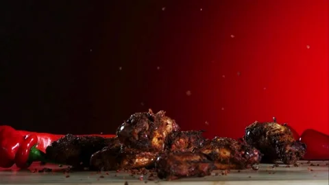 Roasted chicken wings fall onto a table with red peppers Stock Footage 326628131