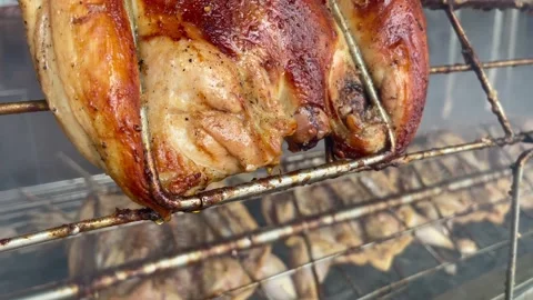 Roasted chickens on spit grilled over fire of a big barbecue Stock Footage 154847594