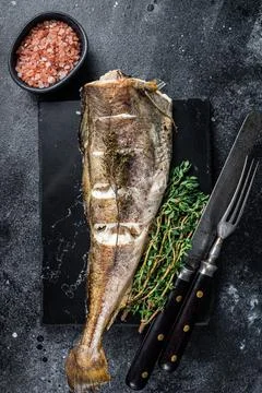 Roasted cod white fish with thyme on marble board. Black background. Top view Stock Photos