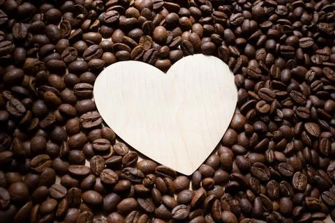 Roasted coffee beans and an empty wooden heart. Place for your text and label Stock Photos